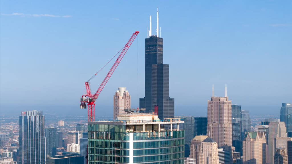 Drone photograph of Chicago skyscraper construction with final glass windows being installed at sunset